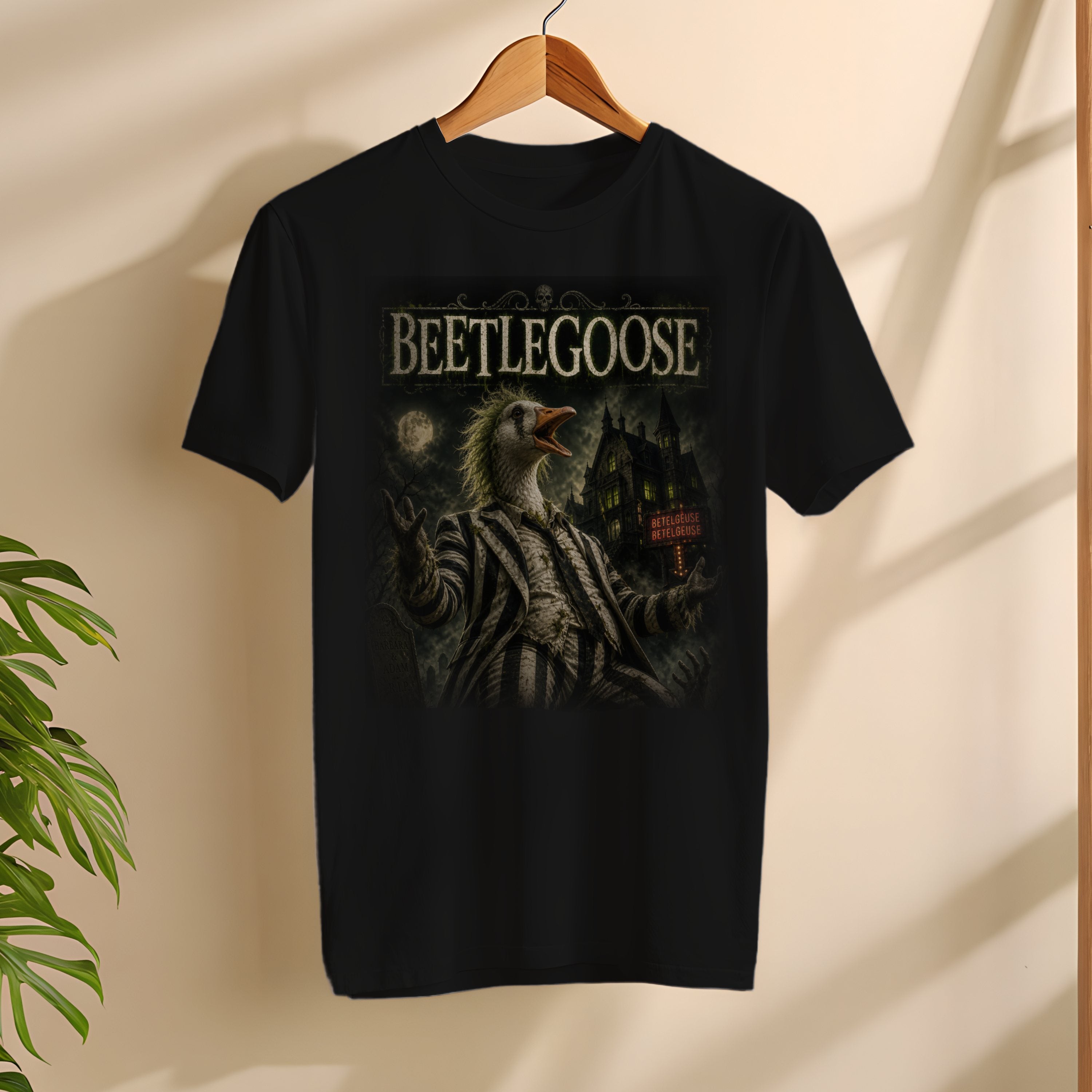 Black t-shirt with 'Beetlegoose' graphic design on a wooden hanger against a beige wall.