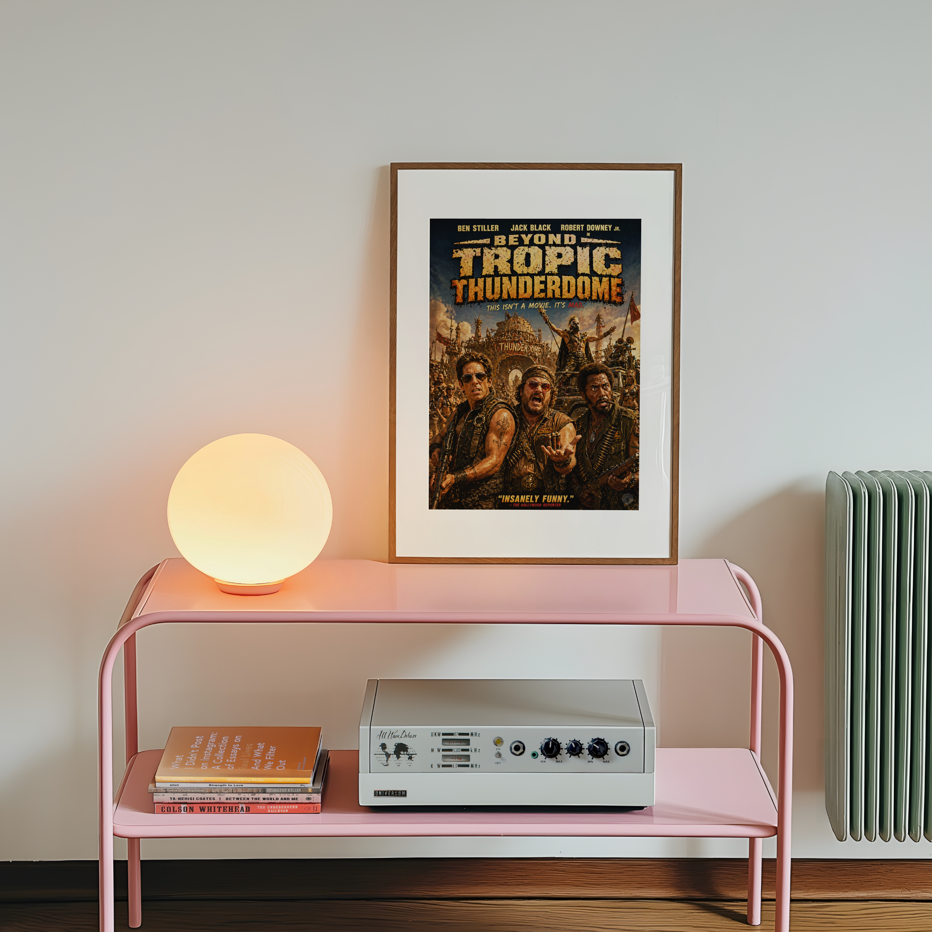 Pink console table with a lamp, books, and a framed movie poster on a white wall.