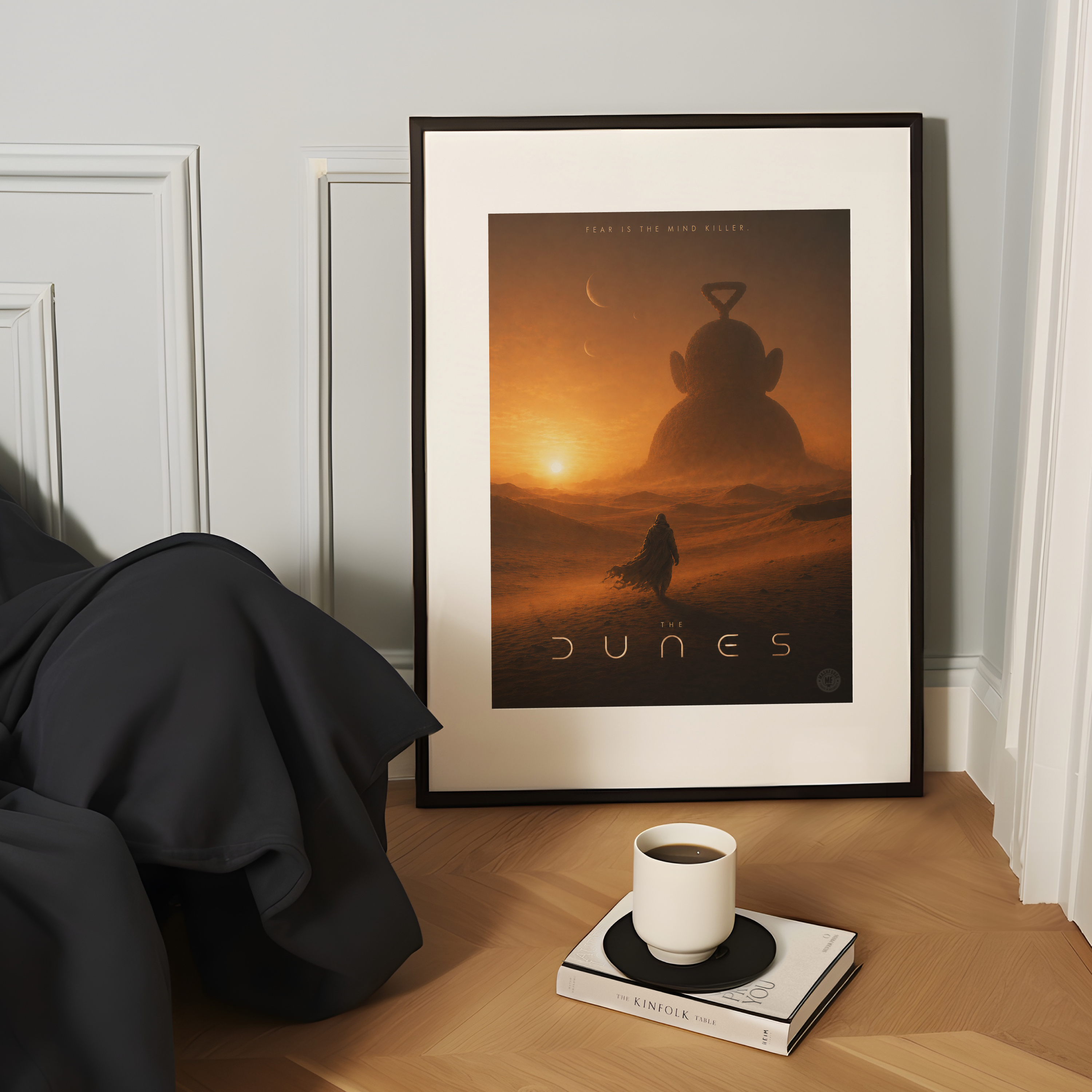 Framed movie poster of 'The Dunes' on a wooden surface with a cup and book.