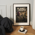 Framed funny parody movie poster titled 'Planet of the Grapes' on a table with a cup and book.