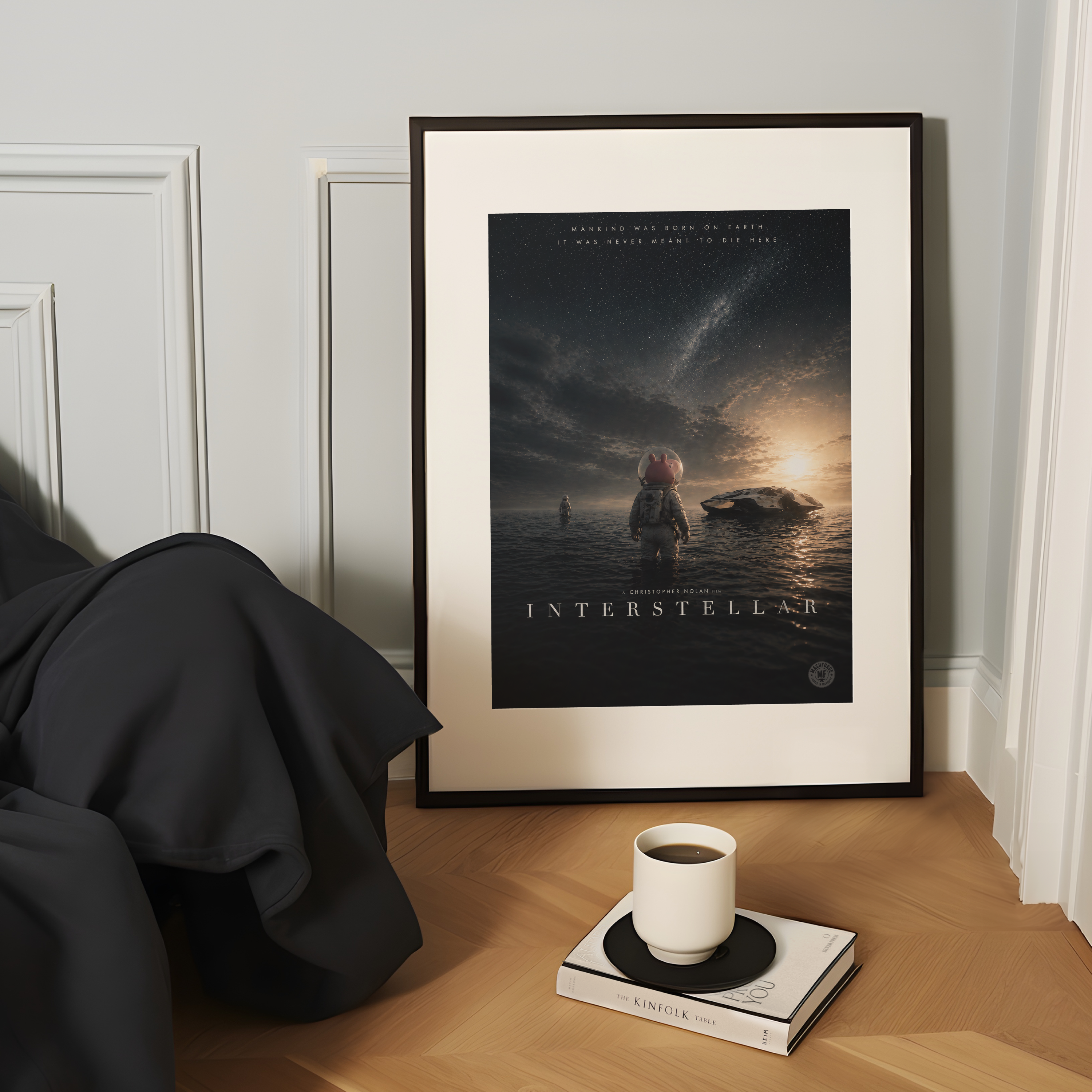 Framed 'Interstellar' movie poster on a wooden surface with a cup and book.