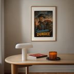 Framed poster of Spockidale Dundee on a wall above a wooden table with a lamp, book, and candle.