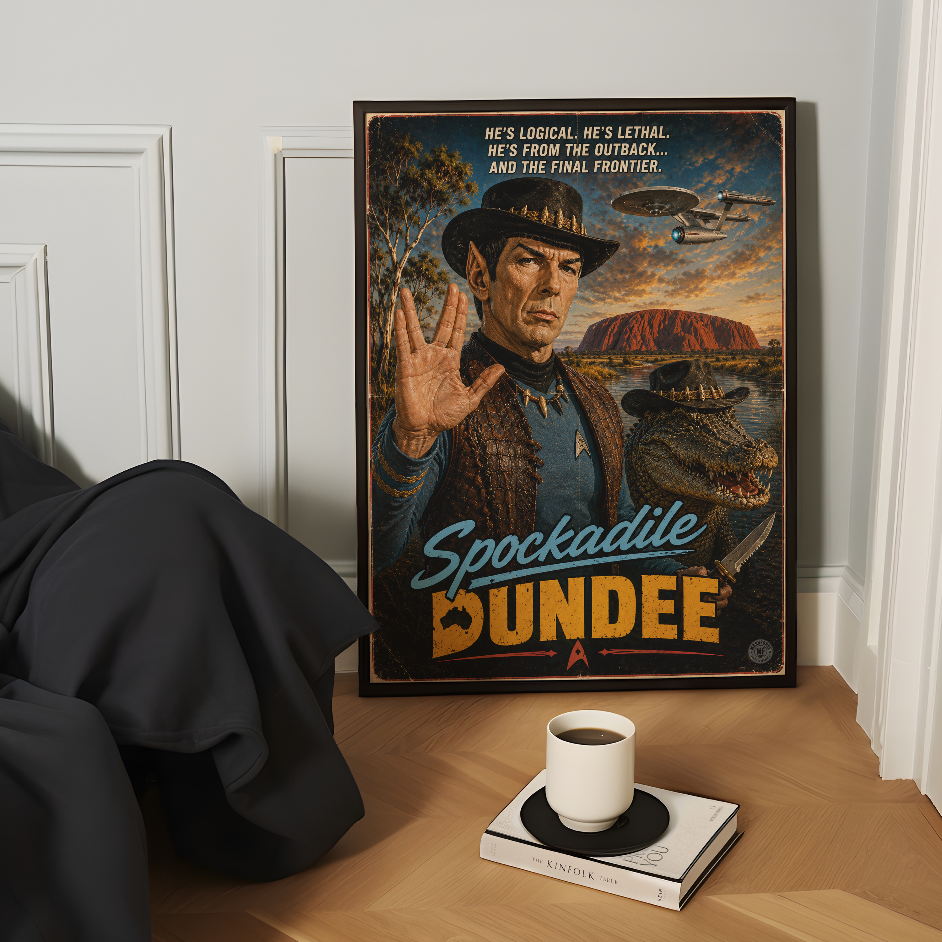 Framed poster of an australian spock character with spockadile dundee text and landscape, placed on a wooden surface with a cup and book.