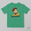 A green crewneck t-shirt featuring a graphic print of Captain Tam O'Shatner from Star Trek wearing a red tartan beret and a gold command uniform, with 'TAM O'SHATNER' printed below. The t-shirt is displayed flat against a neutral gray background.