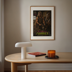 Framed poster of 'The Ultimate Farrier' on a wall above a wooden table with a lamp, book, and candle.