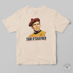 A cream-colored crewneck t-shirt featuring a graphic print of Captain Tam O'Shatner from Star Trek wearing a red tartan beret and a gold uniform, with the text 'TAM O'SHATNER' printed below. The t-shirt is displayed flat against a neutral gray background.