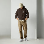 Person wearing a maroon hoodie with MashForge logo, beige cap, and brown cargo pants against a white background