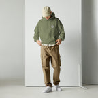 Person wearing a green hoodie with mashforge logo and brown cargo pants on a white background
