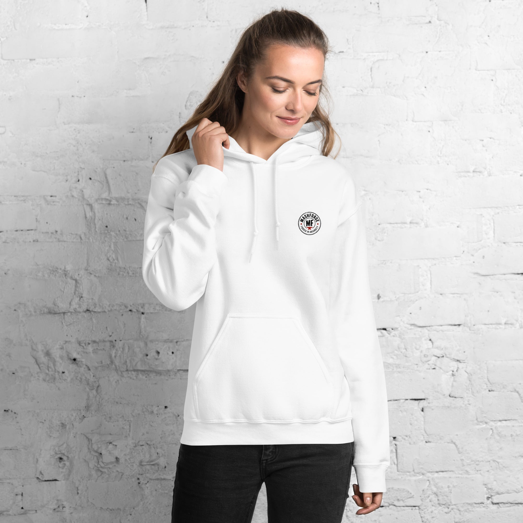 Woman wearing a white mashforge hoodie with a logo against a white brick wall