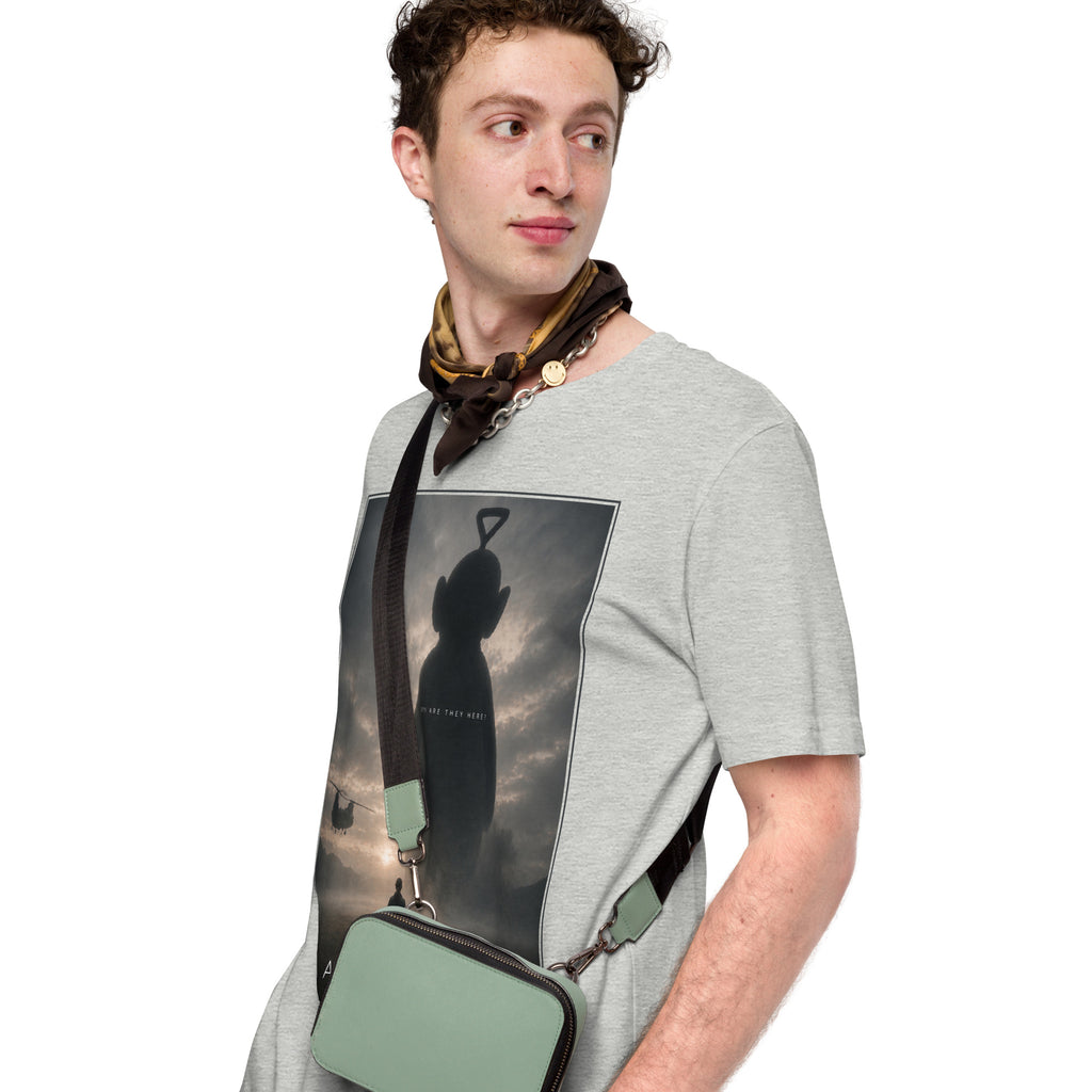 Man wearing a gray t-shirt with a graphic design, holding a green bag.