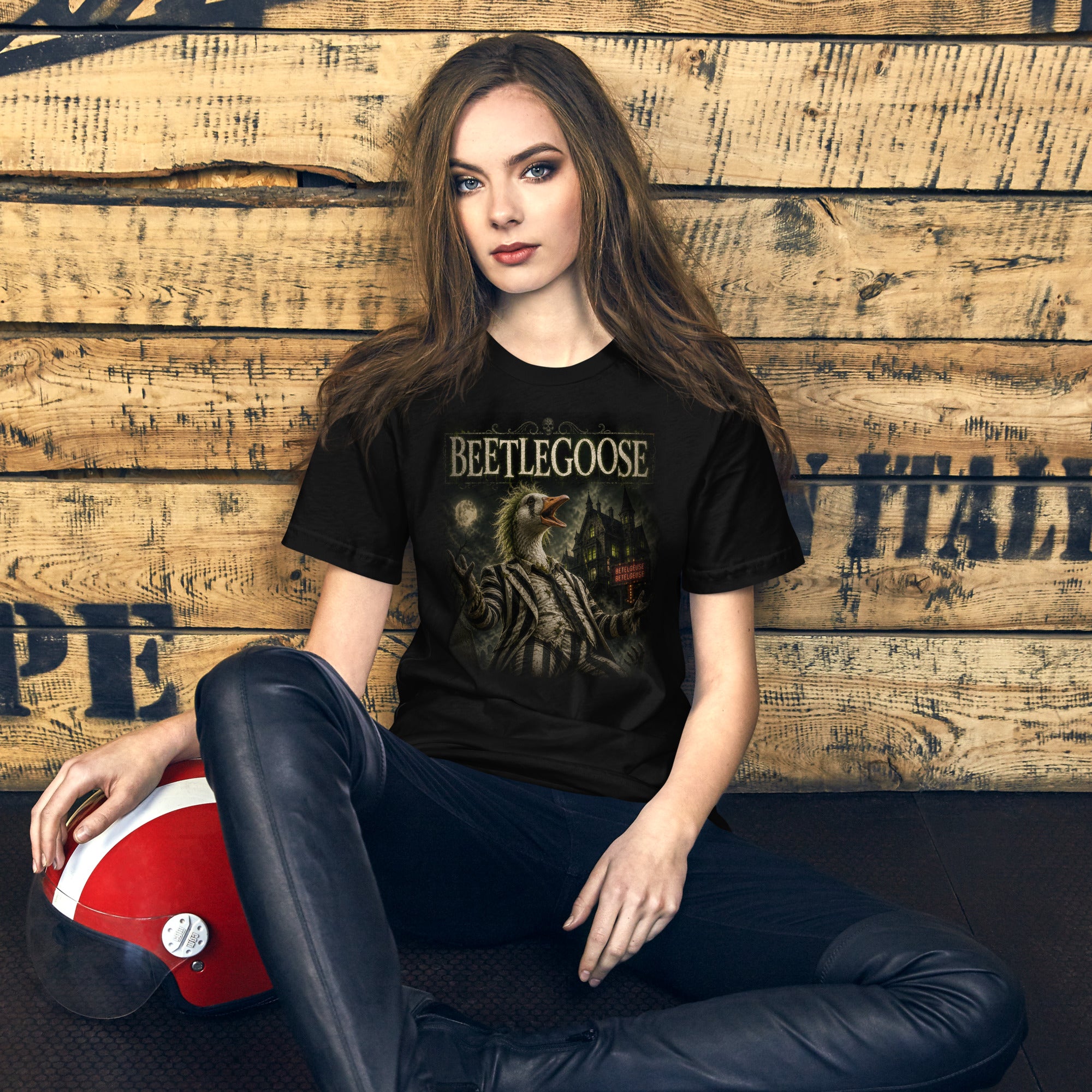 Woman wearing a black t-shirt with a design, sitting against a wooden wall.