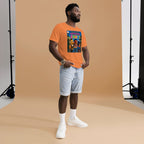 Man wearing an orange t-shirt with a graphic design, standing against a brown backdrop.