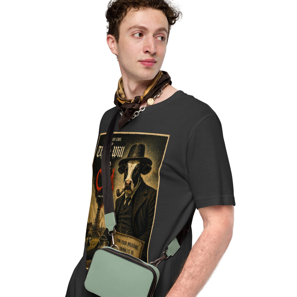Man wearing a black t-shirt with a graphic design of a cow in a hat and scarf, holding a green bag.