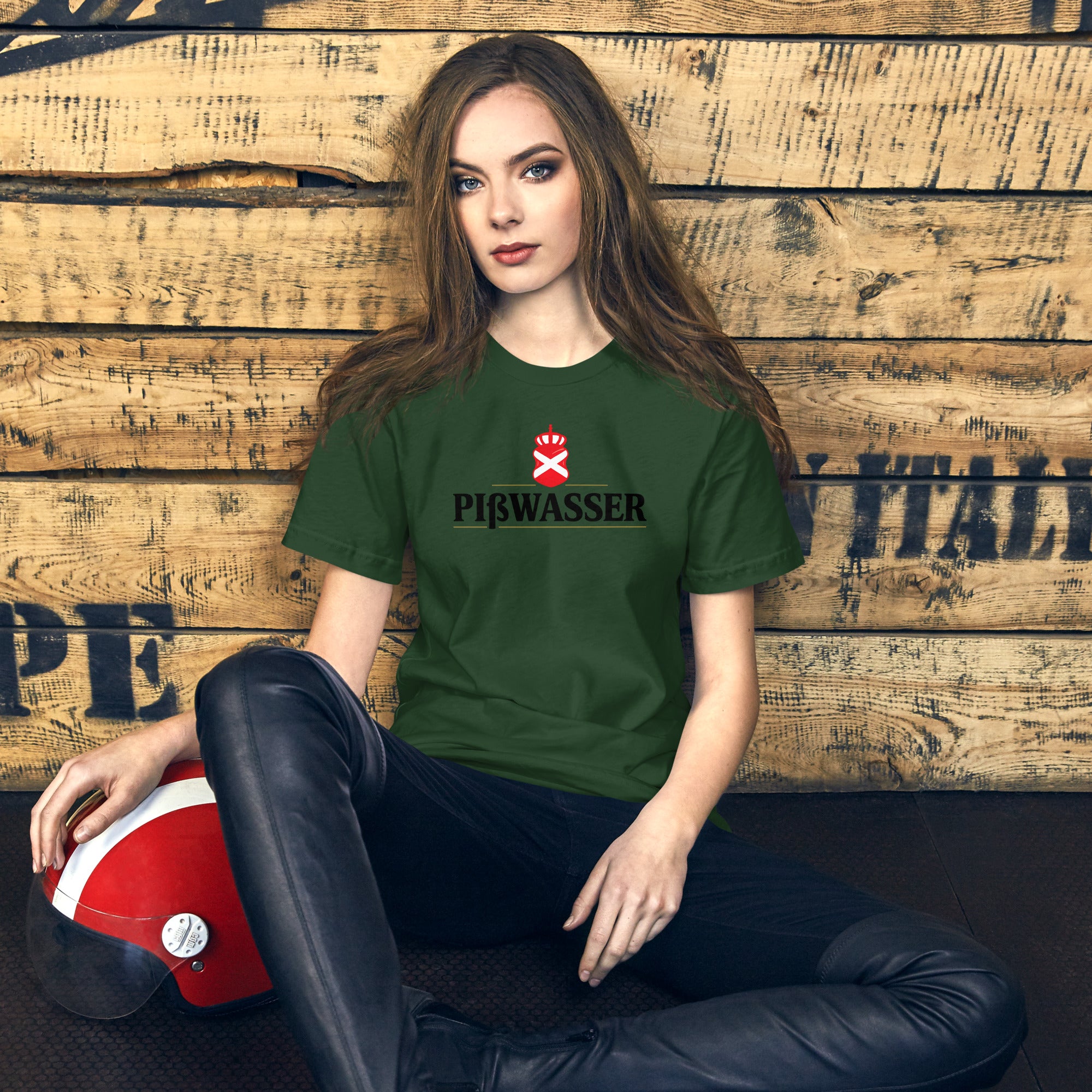 Woman in a green t-shirt sitting against a wooden wall with a helmet on her lap.