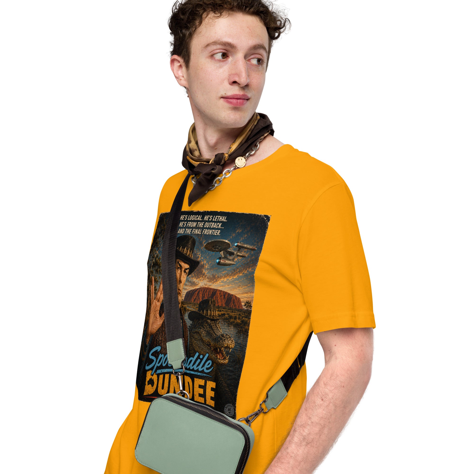 Man wearing a mustard yellow t-shirt with a graphic design, holding a green bag.