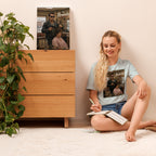 Woman sitting on the floor reading a book with a wooden dresser and plant in the background