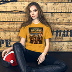 Woman wearing a yellow t-shirt with Beyond Tropic Thunderdome design, sitting against a wooden wall.
