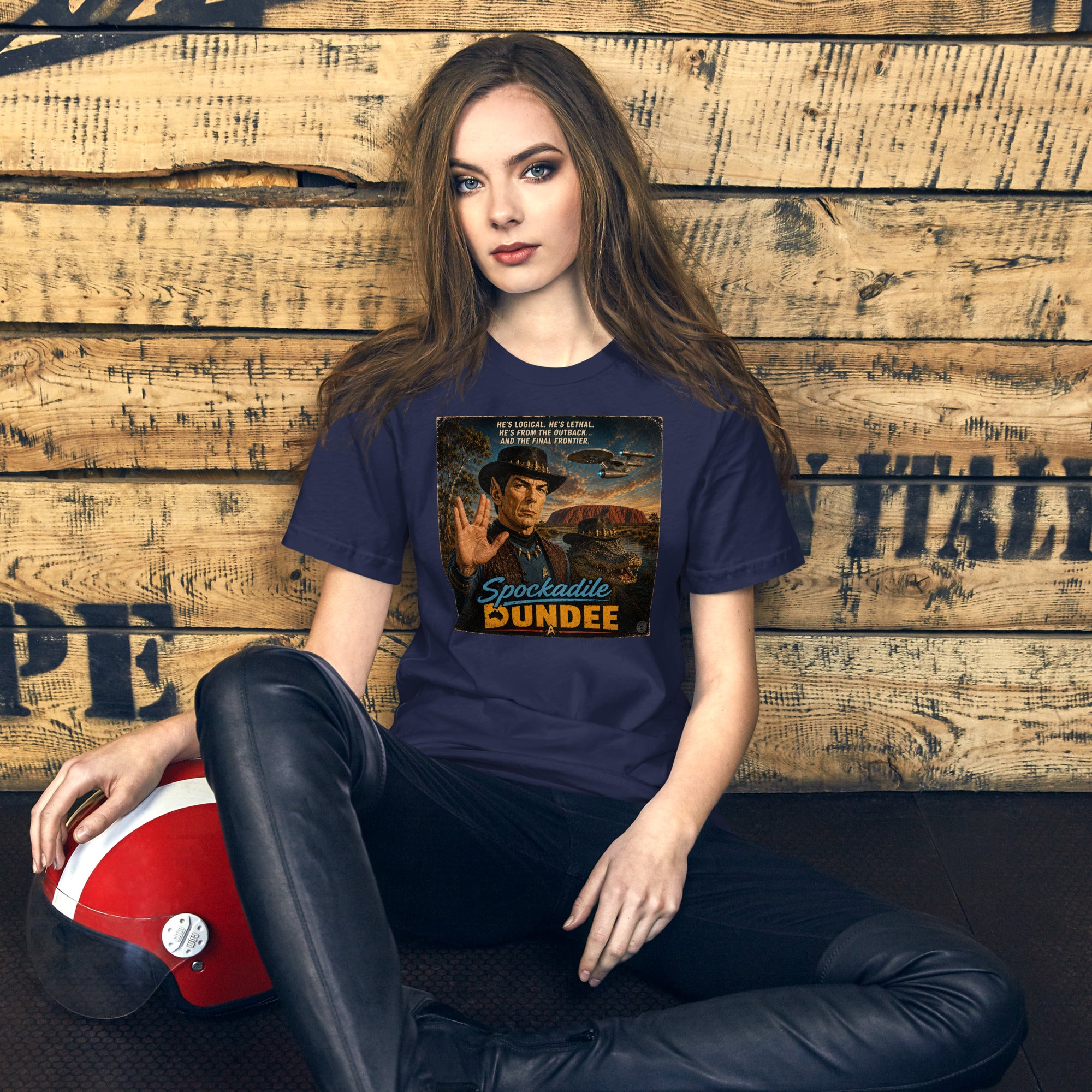 Woman wearing a t-shirt with a graphic design sitting against a wooden wall.