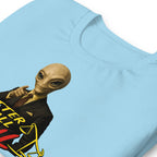 A light blue t-shirt featuring a graphic print of a bald alien in a black suit with a yellow tie and red shirt, pointing to a yellow scale of justice, with the text Better Call Paul partially visible.