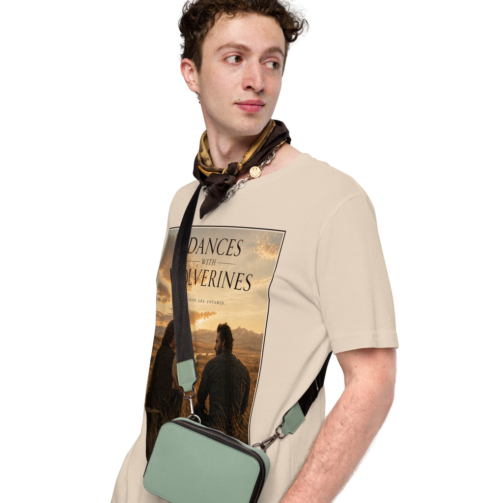 Man wearing a beige t-shirt with a graphic design and a green bag.