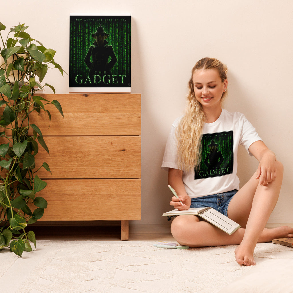 Woman sitting on the floor with a book, wearing a white t-shirt with a graphic design, in a room with a wooden dresser and plant.