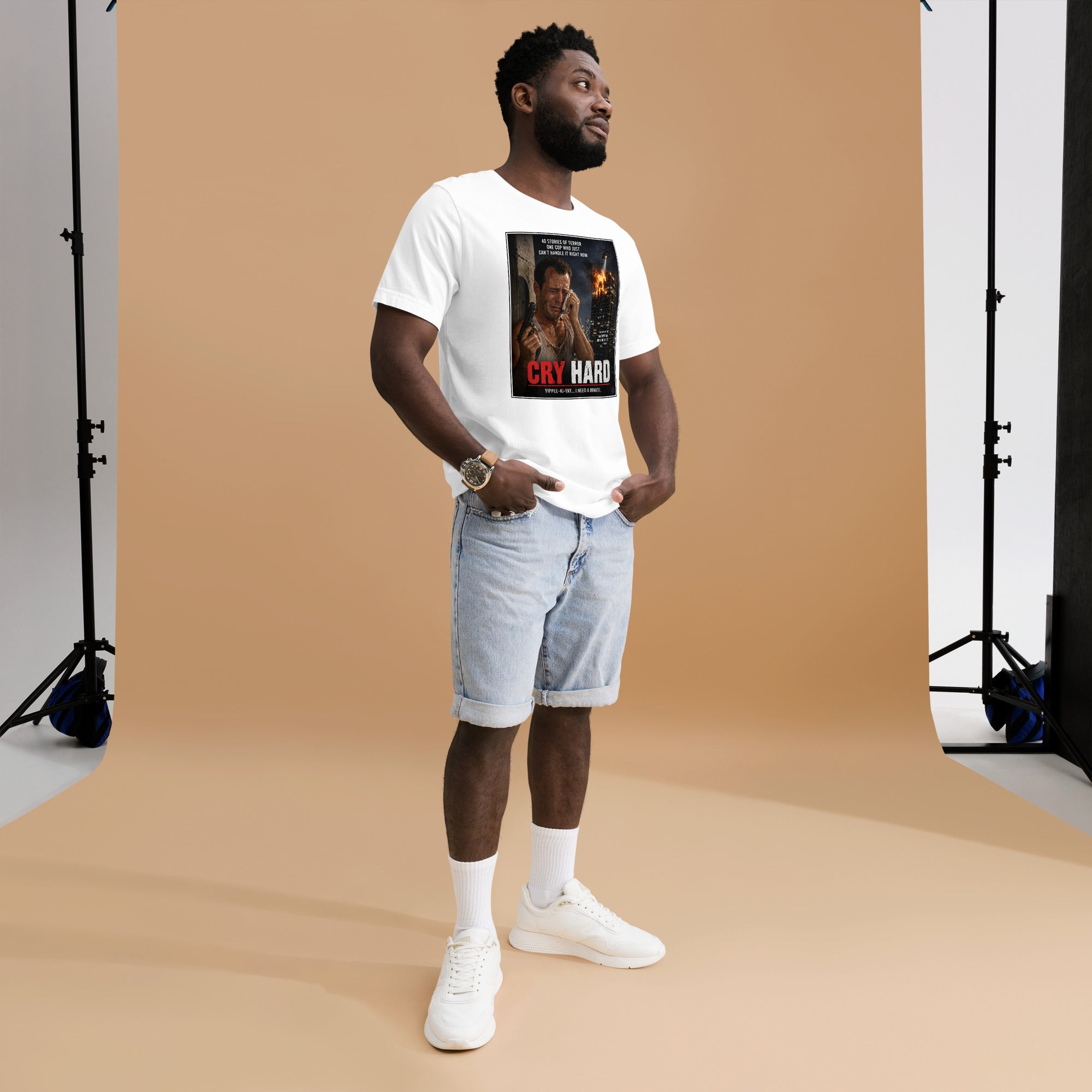 Man wearing a white t-shirt with a graphic design, standing against a brown backdrop in a studio setting.
