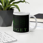 Mug with Matrix-themed design on a desk with keyboard, plant, and notebook.